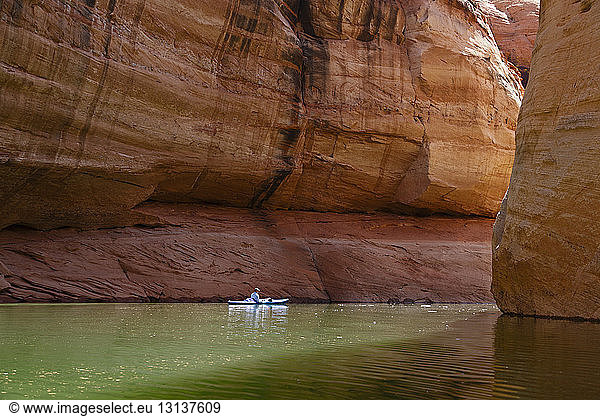 Side view of hiker kayaking on Lake Powell against canyons