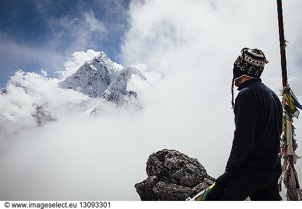 Side view of hiker standing on mountain against cloudy sky at Sagarmatha National Park