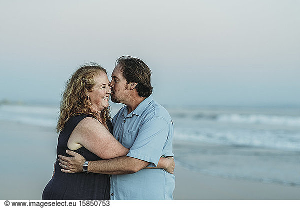Side view of husband and wife kissing each other at the beach
