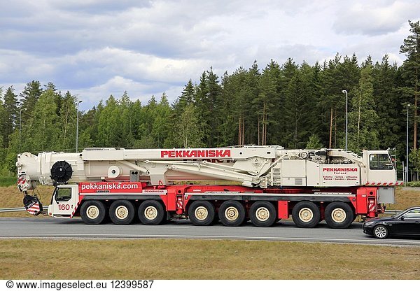 Side view of large Liebherr 8-axle mobile crane of Pekkaniska at speed on road with an overtaking car. Salo  Finland - June 8  2018.