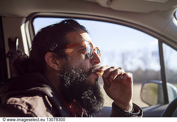 Side view of male hipster smoking electronic cigarette in car