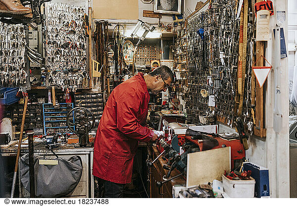 Side view of male locksmith working in repair shop