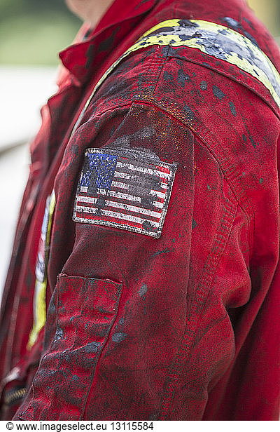 Side view of male worker wearing messy jacket with American flag on sleeve