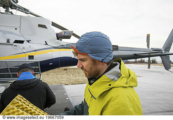 Side view of man packing gear in a helicopter