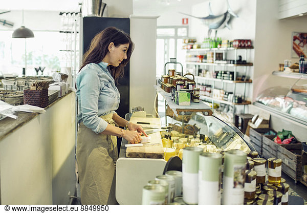 Side view of mature saleswoman at supermarket counter