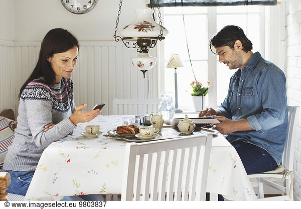 Side view of mid adult couple spending leisure time at breakfast table