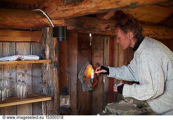 Side view of mid adult woman lighting candle in cottage
