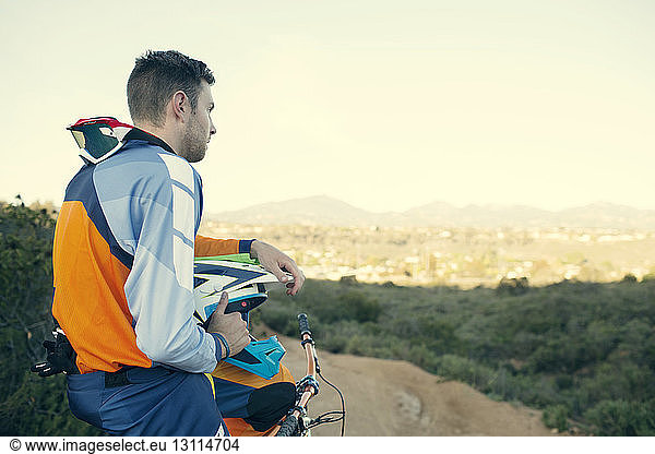 Side view of mountain biker looking at view against sky