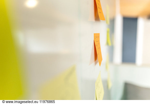 Side view of orange and yellow adhesive notes on whiteboard