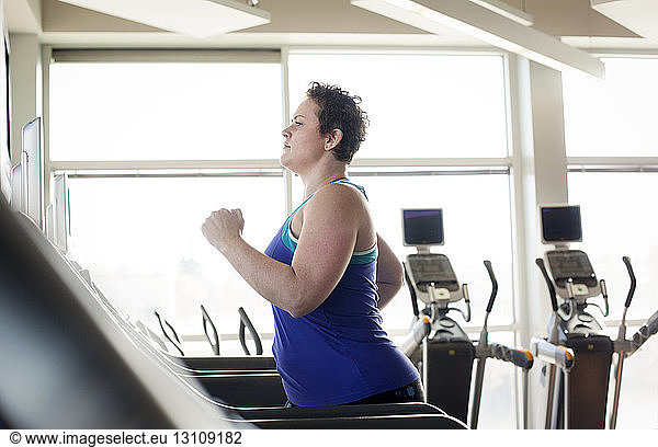 Side view of plus size woman exercising on treadmill