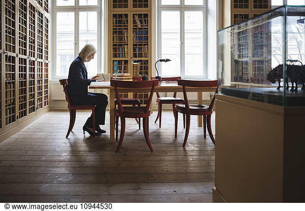 Side view of senior female lawyer reading book in library