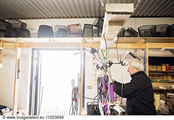 Side view of senior repairman repairing bicycle in workshop