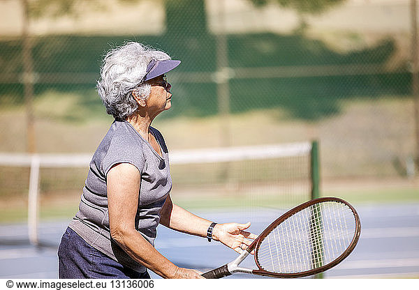 Side view of senior woman holding racket at tennis court