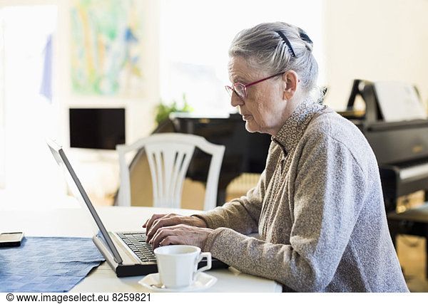 Side view of senior woman using laptop at table