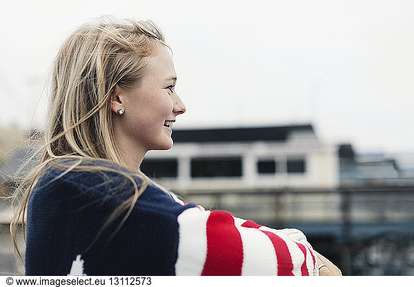 Side view of smiling teenage girl looking away at harbor