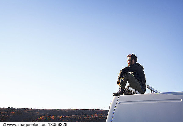Side view of thoughtful man sitting on camper van
