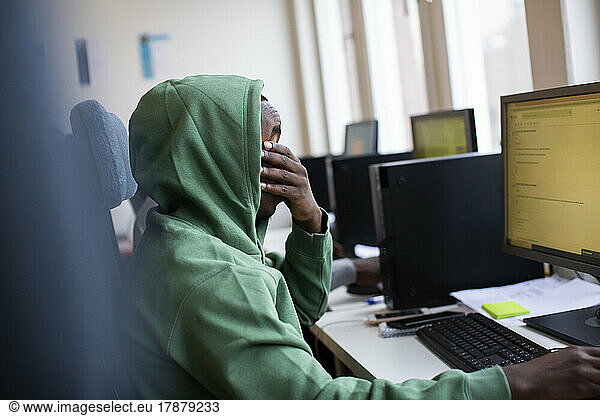 Side view of tired trainee covering eyes while working at office