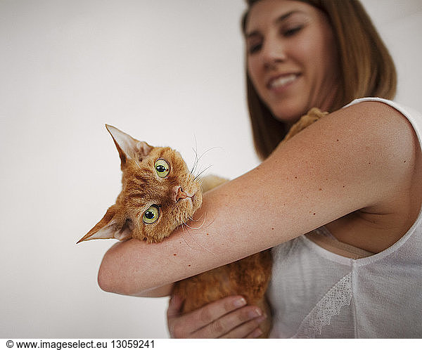 Side view of woman carrying cat at home