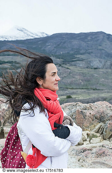Side view of woman enjoying wind against mountain