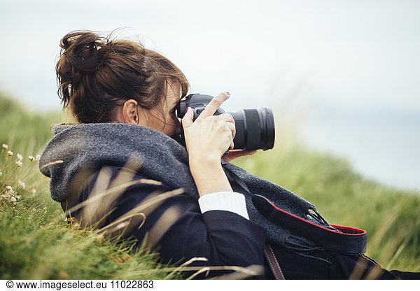 Side view of woman photographing through SLR camera on hill