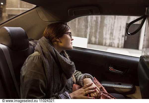 Side view of woman sitting in taxi looking through window