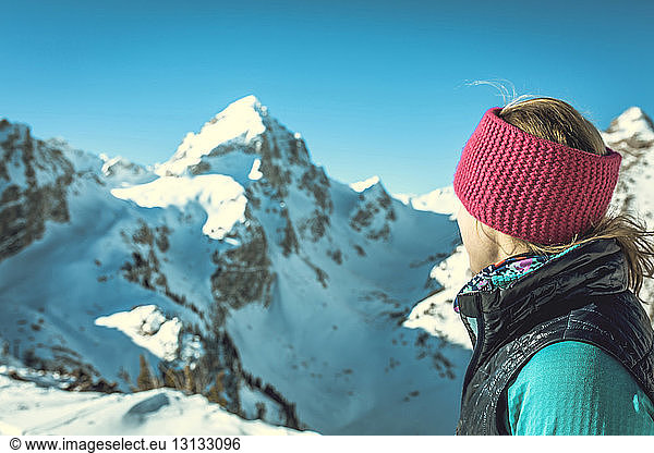 Side view of woman standing against snowcapped mountains