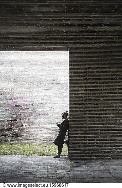 Side view of woman standing by wall