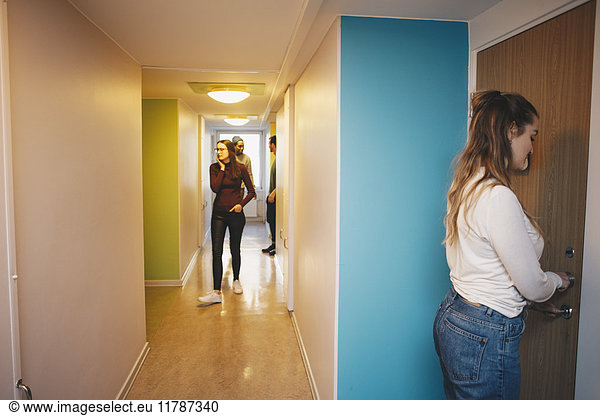 Side view of woman unlocking door standing in college dorm