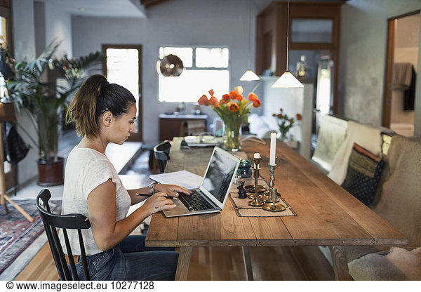 Side view of woman working on laptop at dining table