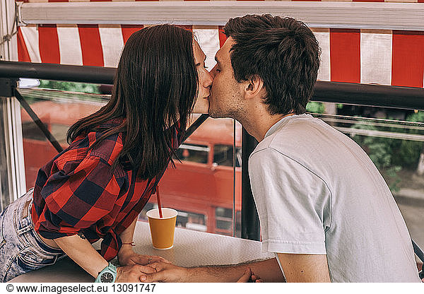 Side view of young couple kissing on mouth at cafe