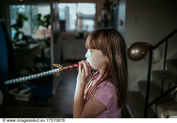 Side view of young girl blowing party horn