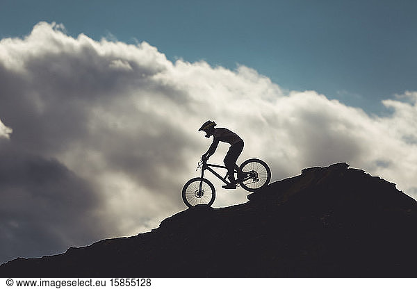 side view of young male on mountain bike riding over rocks in Utah