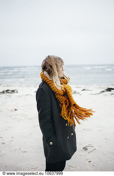 Side view of young woman wearing scarf while looking away at beach