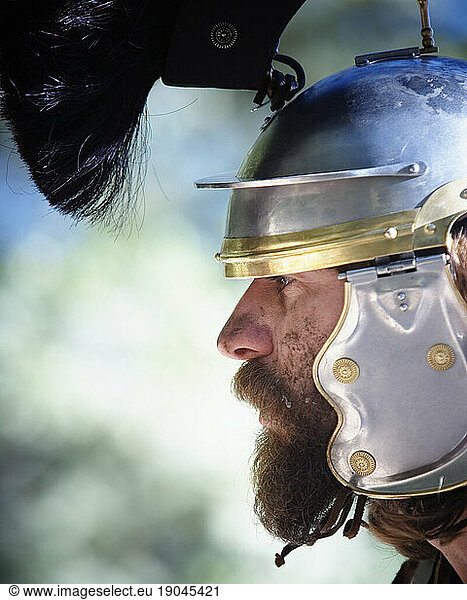 Side view portrait of a man wearing a metal helmet with headdress. California.