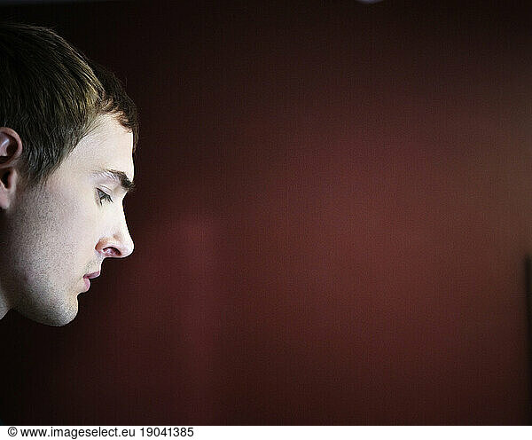 Side view portrait of a young man looking down.