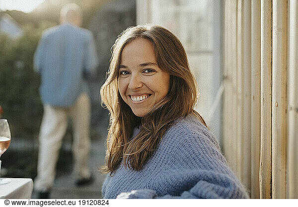 Side view portrait of smiling woman wearing sweater during dinner party at cafe