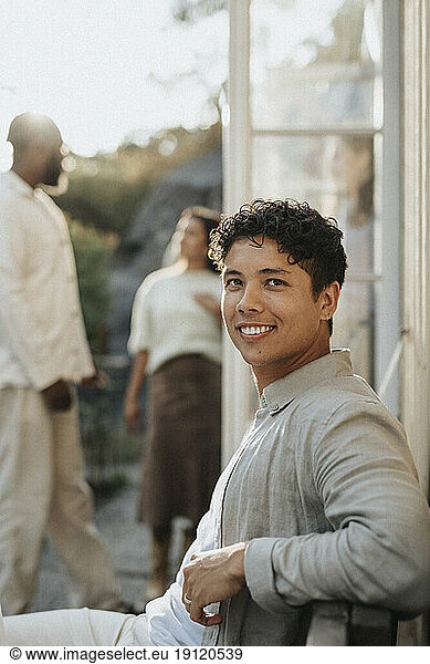 Side view portrait of smiling young man during dinner party at cafe