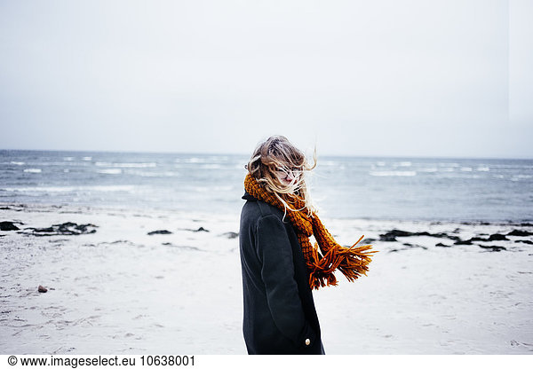 Side view portrait of young woman wearing scarf at beach