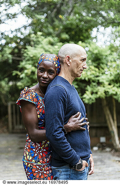 Side view woman wearing african bandana hugging husband by garden