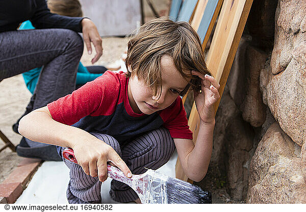 Sieben Jahre alter Junge mit einem Pinsel  der Karton bemalt