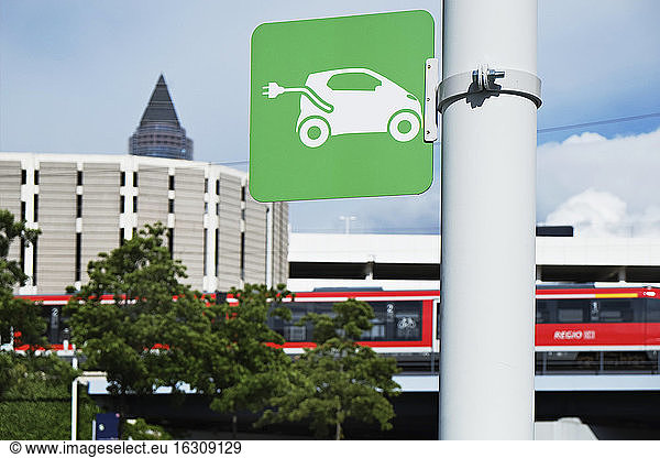 Sign for an electric vehicle charging station with train in background