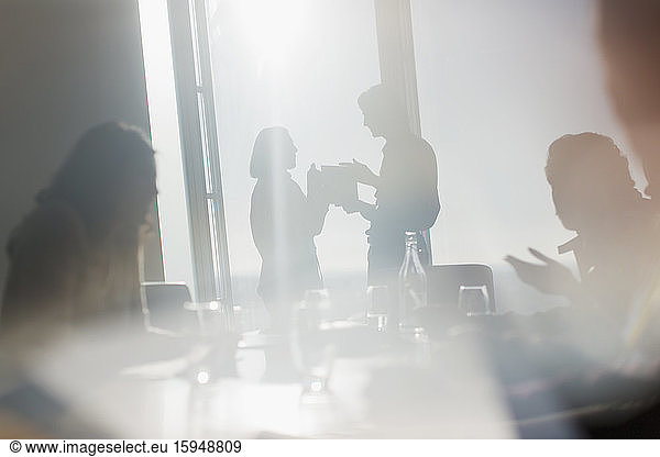 Silhouette business people talking in sunny conference room window