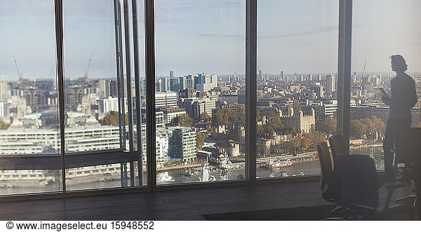 Silhouette businessman at highrise window overlooking city  London  UK
