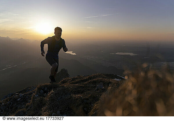 Silhouette hiker running on mountain at sunset