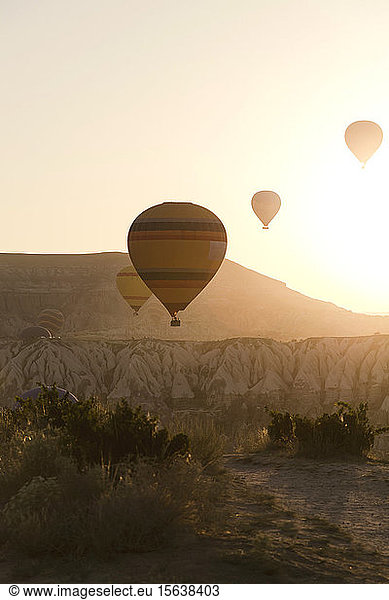 Silhouette hot air balloons flying over landscape against clear sky during sunset at Goreme National Park  Turkey
