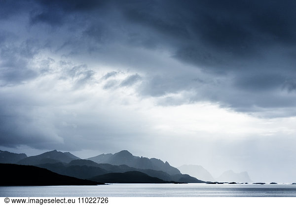 Silhouette mountain range by lake against cloudy sky