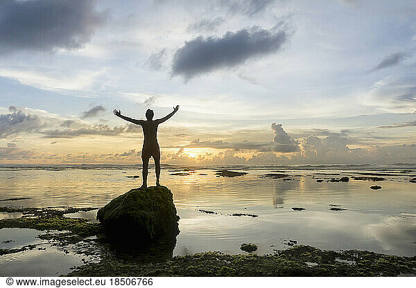 Silhouette of a man arms outstretched at sunset over ocean  Uluwatu  Bali  Indonesia
