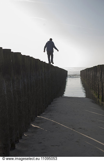 Silhouette of a mature man balancing on wooden post on beach  Renesse  Schouwen-Duiveland  Zeeland  Netherlands