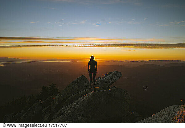 Silhouette of a woman on a mountain peak at sunset