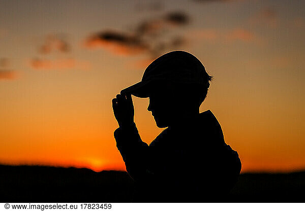 Silhouette of boy with cap at sunset